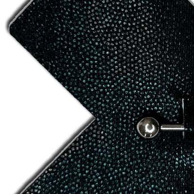 Close-up of a textured black surface of Pastease liquid black cross plus barbell nipple cover with a metallic stud.