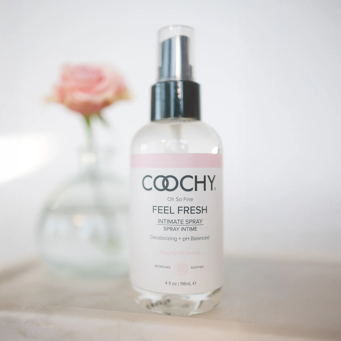 COOCHY intimate spray bottle on a light background with a blurred flower in the background