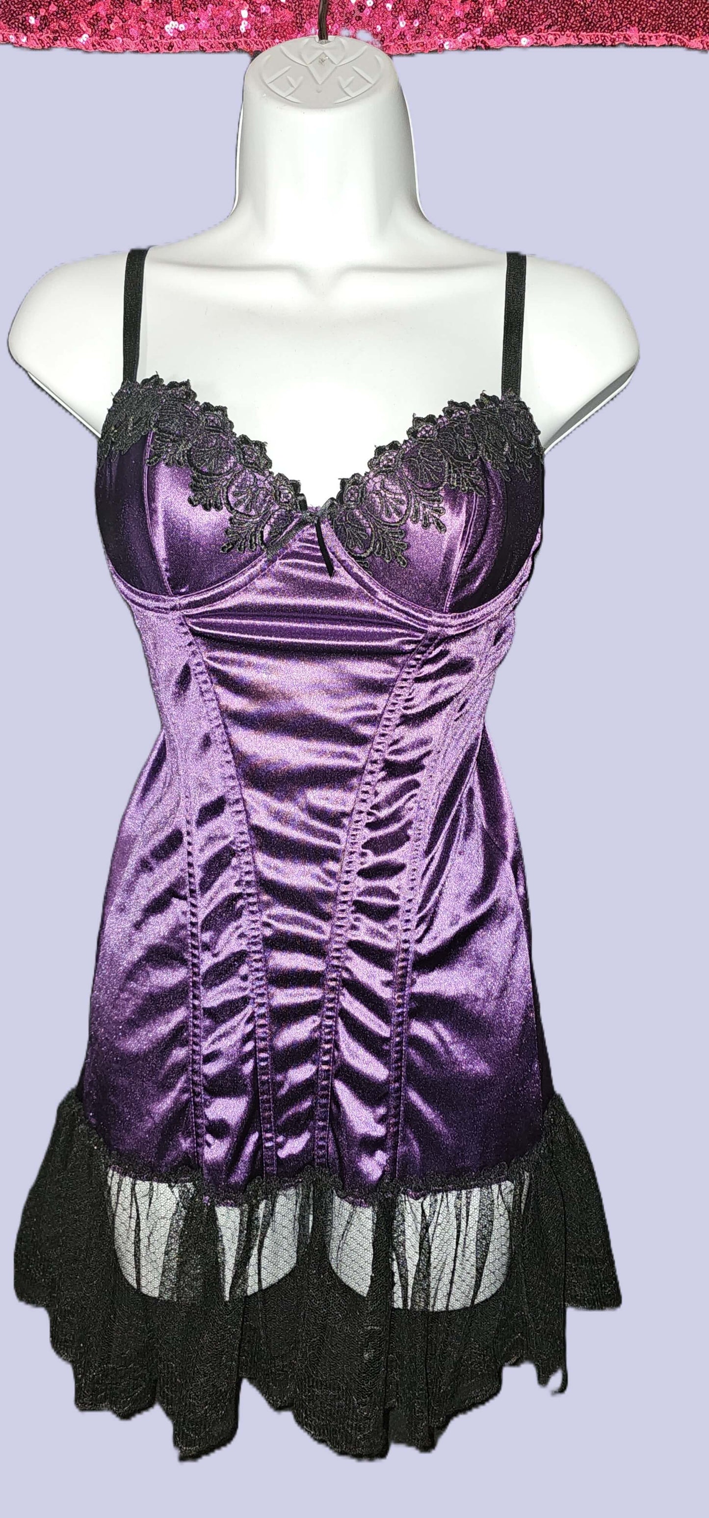 A purple satin corset-style mini dress with black lace trim and black ruffled hem, displayed on a white mannequin torso against a light lavender background. Escante Luxury Lace Purple Babydoll Dress with Matching Thong - Medium