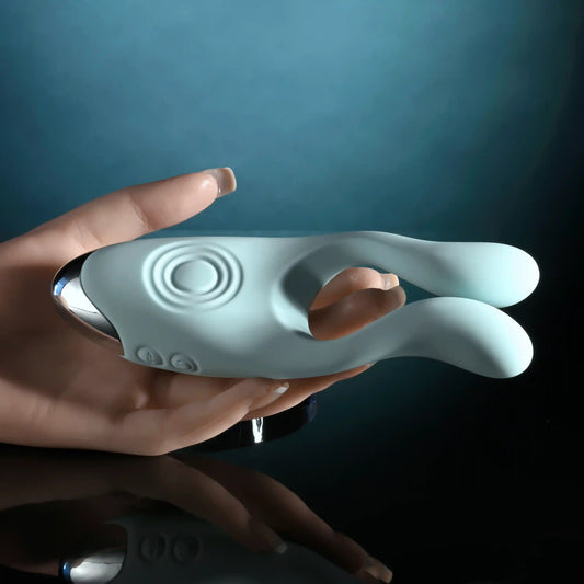 Hand holding Evolved Nevelties Couples Therapy vibrator, a light blue vibrator against a dark background