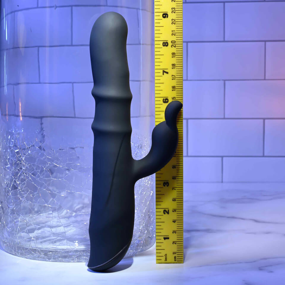 Black Evolved Novelties Ringmaster rabbit vibrator with a yellow ruler for scale against a tiled wall background