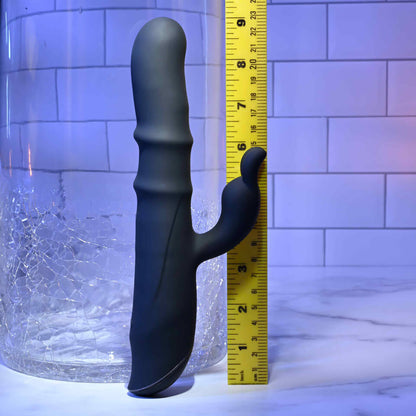 Black Evolved Novelties Ringmaster rabbit vibrator with a yellow ruler for scale against a tiled wall background