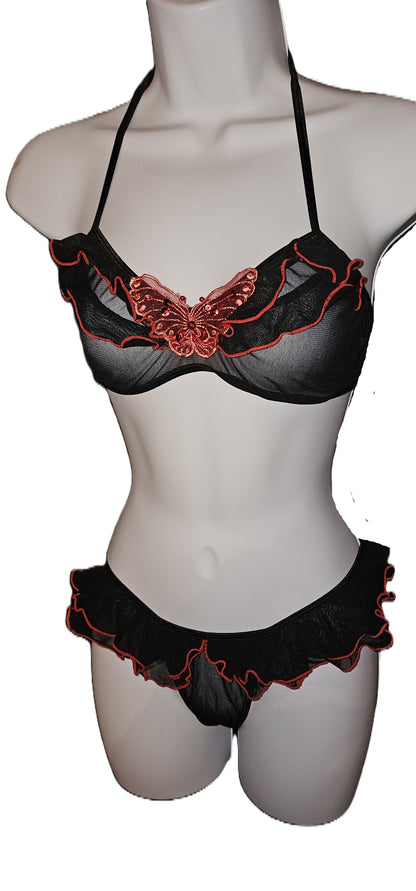 Black lingerie set with red embroidered butterfly details on a mannequin torso, featuring a sheer mesh bralette and matching ruffled panties. Vintage Leg Avenue black halter bra top and ruffle thong lingerie set with red sequin butterfly accent