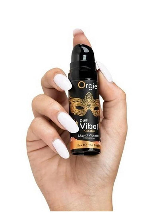 Hand holding a bottle of 'Orgie Dual Vibe' liquid vibrator with a white background at Texas Love Shop