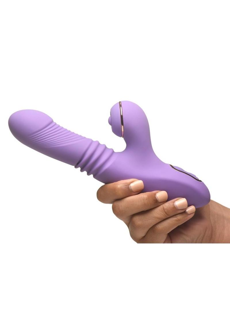 Purple Shegasm Pro-Thrust Max Rechargeable Silicone Thrusting & Pulsing Rabbit vibrator held by a hand on a white background