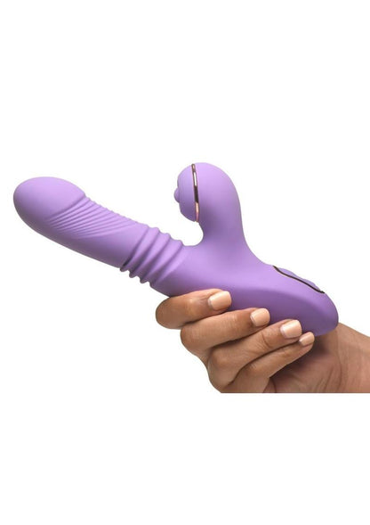 Purple Shegasm Pro-Thrust Max Rechargeable Silicone Thrusting & Pulsing Rabbit vibrator held by a hand on a white background
