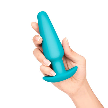 Large Teal silicone anal plug by b-vibe held in a hand against a white background. 