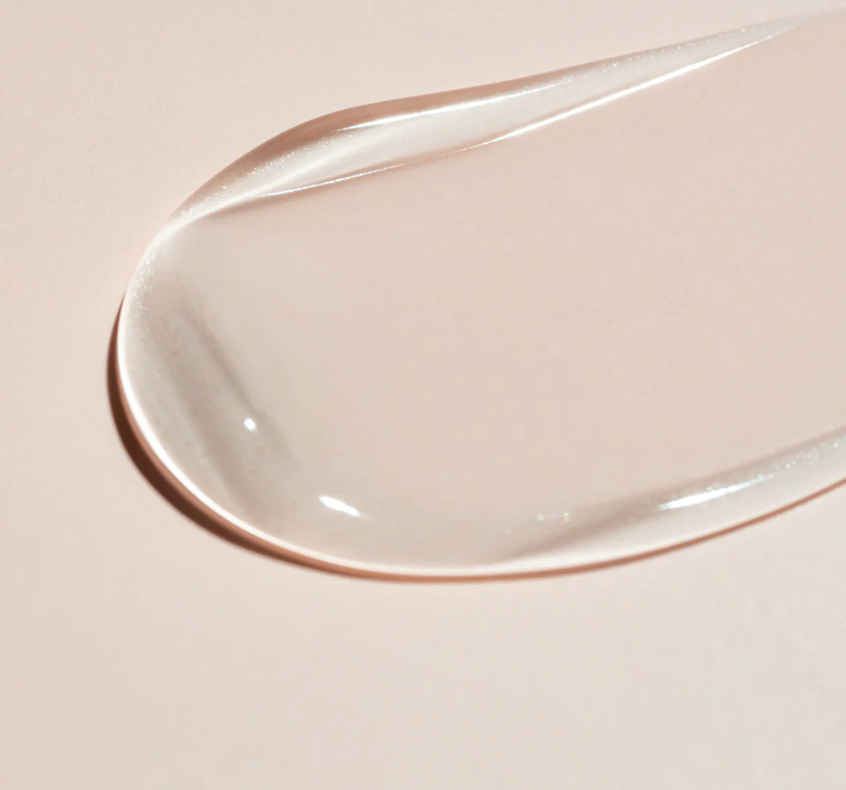 Close-up of a smooth, silky clear Beaver Butter Ingrown Hair Serum on a light pink background