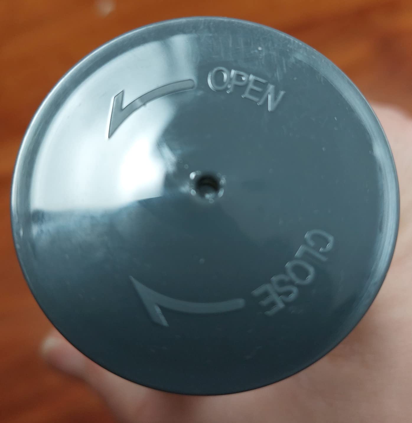 Close-up of Coochy Gogo Coco ultra hydrating body scrub twist to open lid with 'Open' and 'Close' labels on a wooden surface