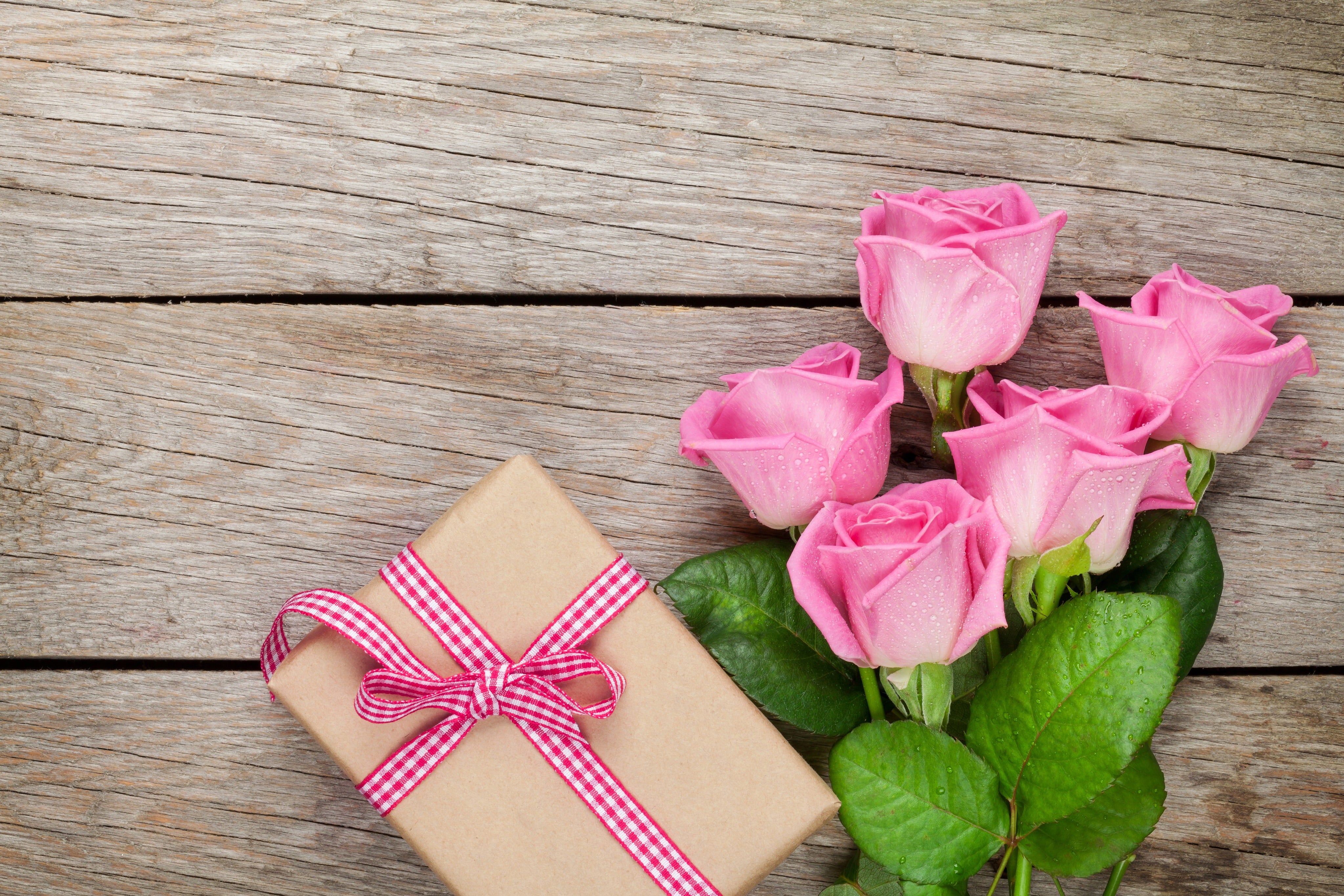 Pink ribbon gift box with roses on wooden table, a romantic surprise, couples’ gift, intimate luxury present.