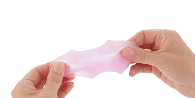 Hand holding X5 Men Goin' Down pink BJ Masturbator silicone oral sex and bj enhancer, stretching it between two hands on a white background