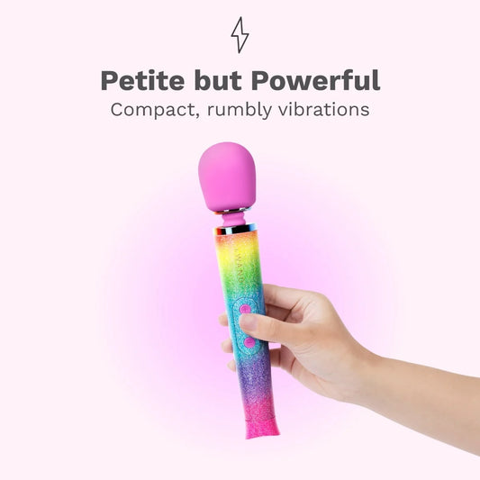Colorful handheld Le Wand Petite Rainbow Ombre vibrator held by a hand with text 'Petite but Powerful' on a pink background