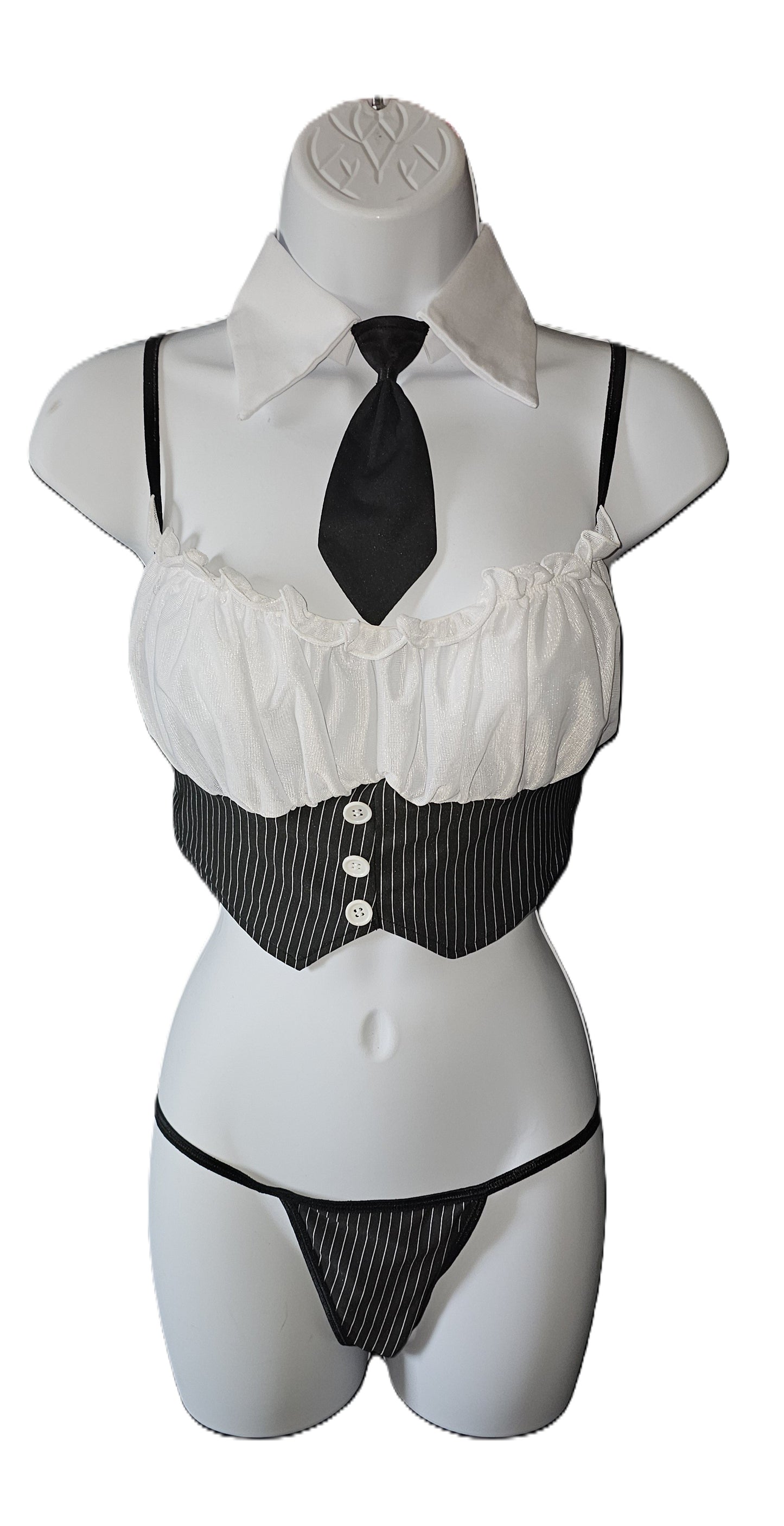 A ladies costume lingerie set displayed on a white mannequin torso, featuring a white ruffled shirt top with a black tie, a black and white pinstripe vest, and matching black and white pinstripe thong. Dreamgirl 4-piece pinstripe lingerie set with chiffon camisole, attached necktie, and decorative buttons