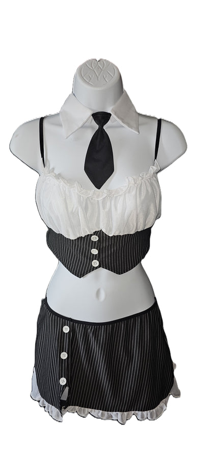 A women's gothic ceo, mafia pinstripe cosplay costume displayed on a white mannequin torso. The costume features a white ruffled blouse with a black collar and tie, a black and white pinstriped corset-style waist panel with white buttons, and a matching black and white pinstriped mini skirt with white buttons and a ruffled hem. Dreamgirl 4-piece pinstripe lingerie set with chiffon camisole, attached necktie, and decorative buttons