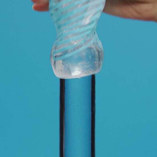 Tenga Spinner DX male stroker in action with woman's hand sliding it on glass pole on a blue background.