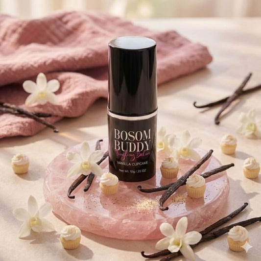 Bosom Buddy Vanilla Cupcake product on a pink stone surface with vanilla beans and flowers.
