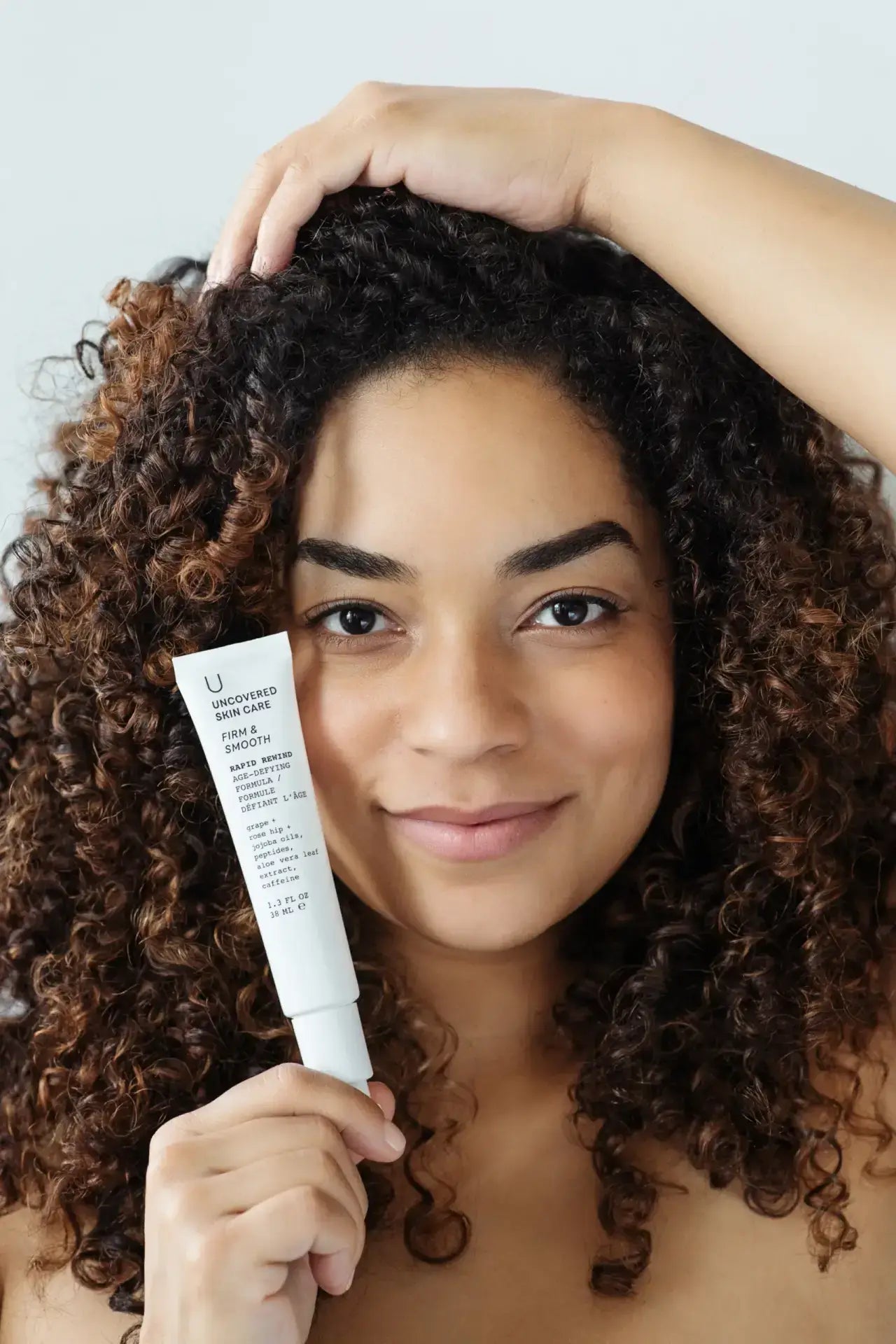 Woman holding a Pure Romance Rapid Rewind anti-aging skincare product with a neutral background