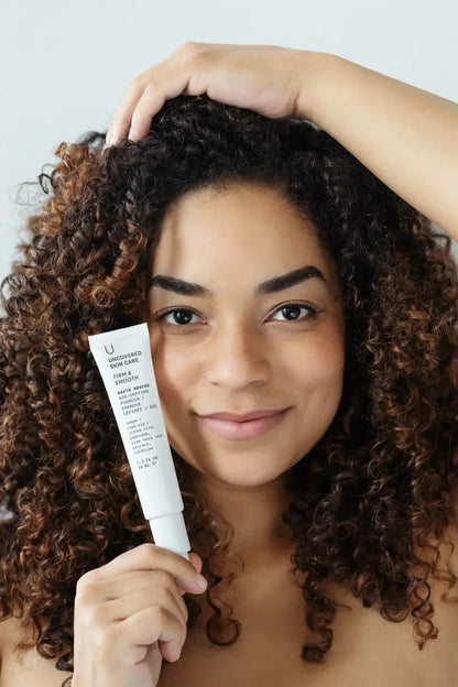 Woman holding a Pure Romance Rapid Rewind anti-aging skincare product with a neutral background