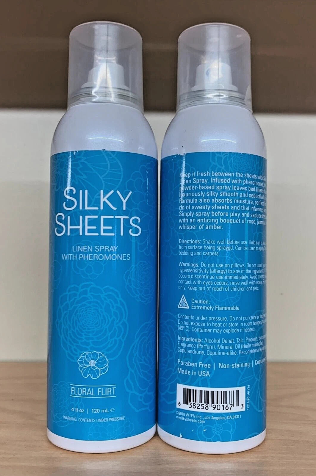 Two bottles of 'Silky Sheets' linen spray with blue labels on a wooden surface.