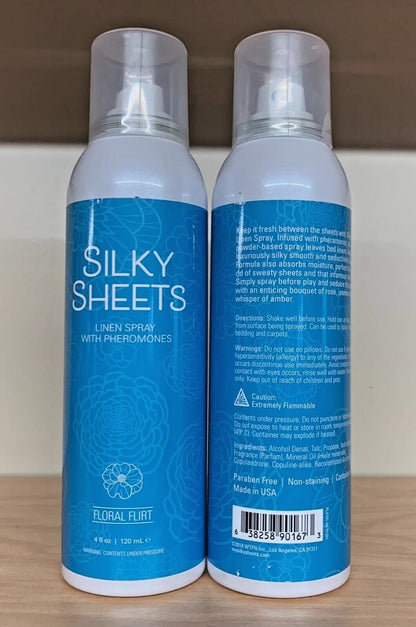 Two bottles of 'Silky Sheets' linen spray with blue labels on a wooden surface.