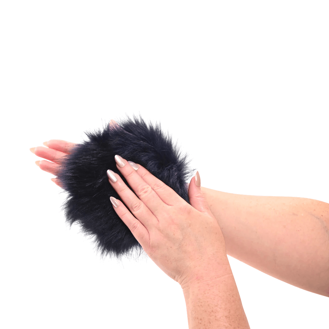 Sportsheets cougar spiked sensory glove in Black like fur pom-pom mitten with hidden spikes held between two hands on a white background