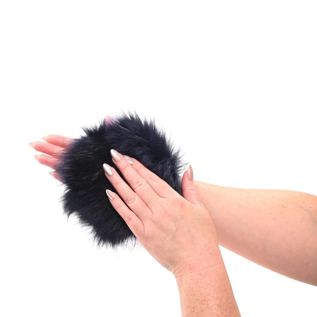 Sportsheets cougar spiked sensory glove in Black like fur pom-pom mitten with hidden spikes held between two hands on a white background