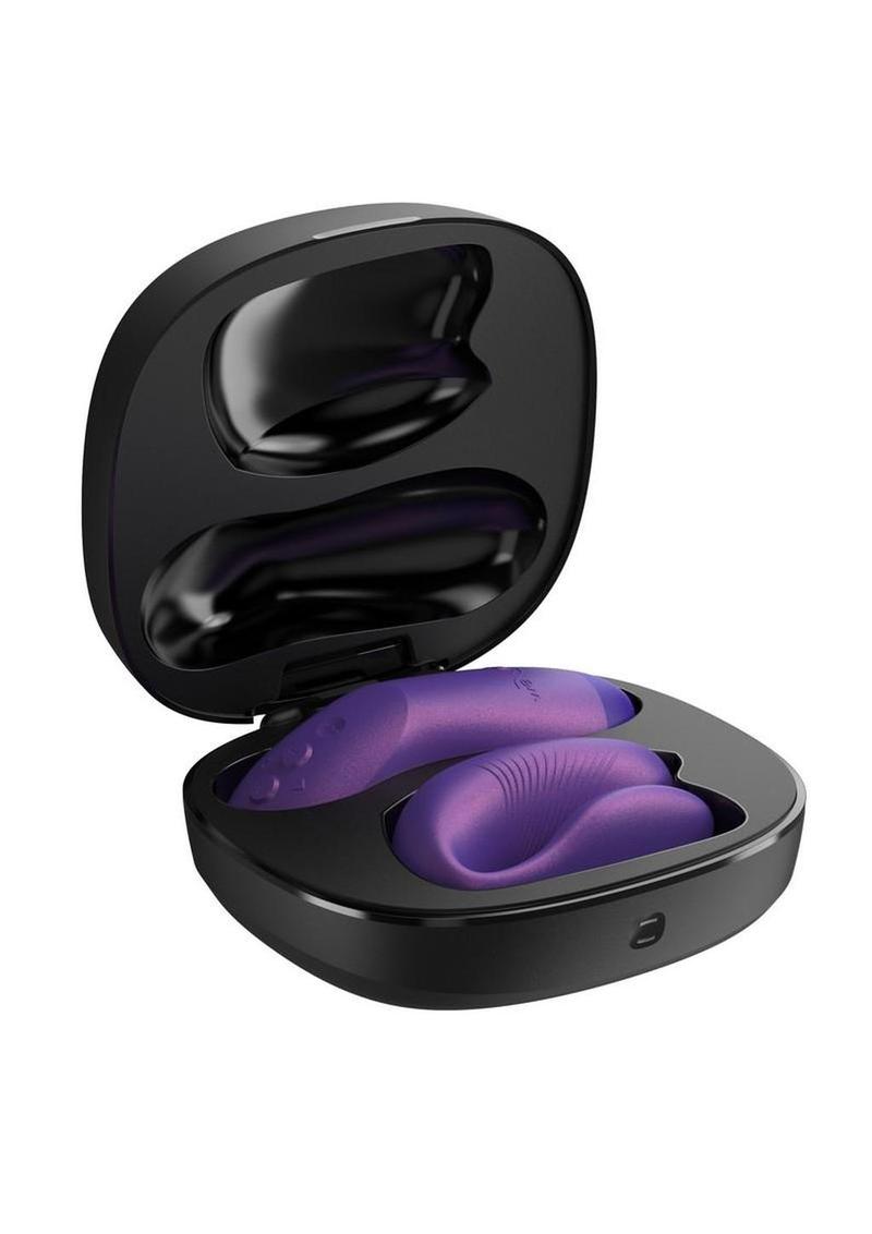Purple We-Vibe Chorus Pro Couples App-Controlled vibrator in black clamshell recharging station with lid open to show item stored inside, on a white background.