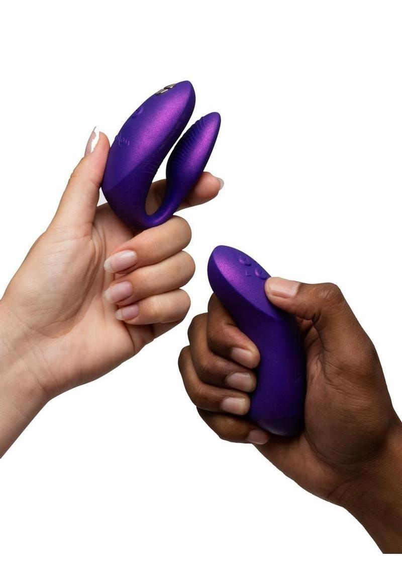 Lifestyle shot of Purple We-Vibe Chorus Pro Couples App- Controlled vibrator in a woman's hand and the remote in a man's hand on a white background.