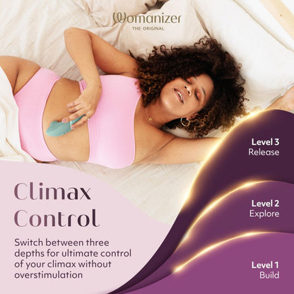 Woman lying on a bed with a product, featuring the brand 'Womanizer'. She is pleased with the Next 3D Climax Control toy.